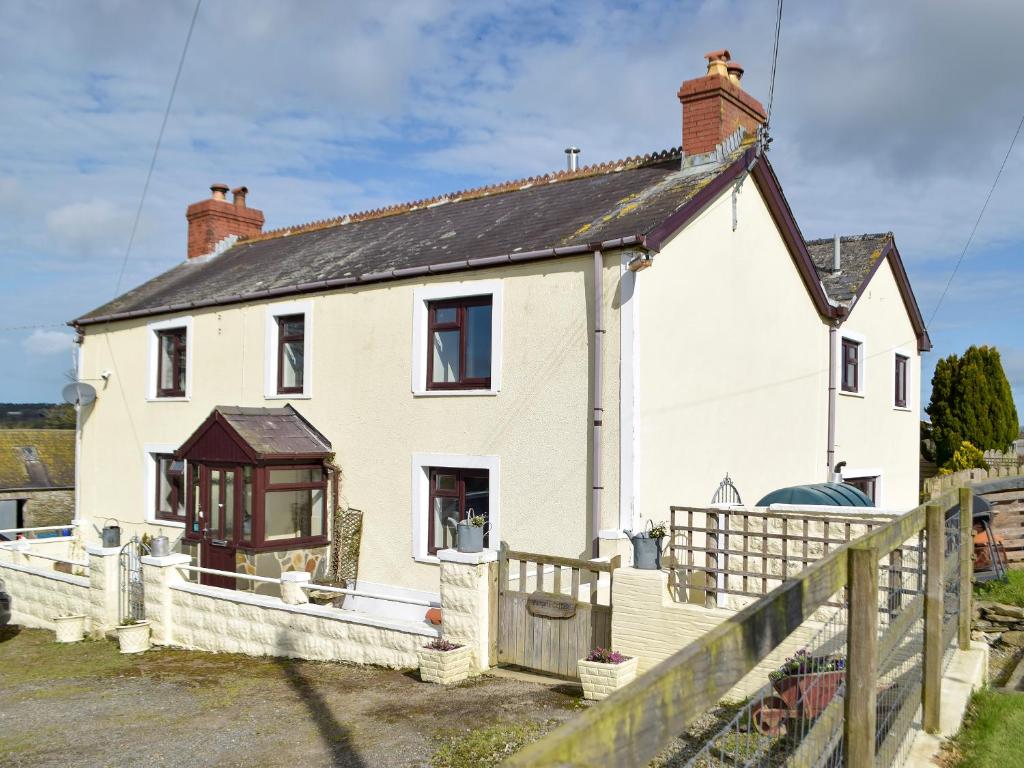 a white house with a wooden fence in front of it at Pengelli Cottage in Eglwyswrw