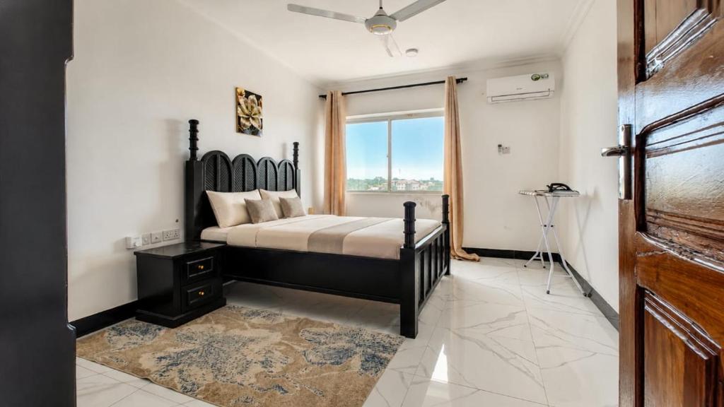 a bedroom with a large bed and a window at City Getaway Apartments in Zanzibar City