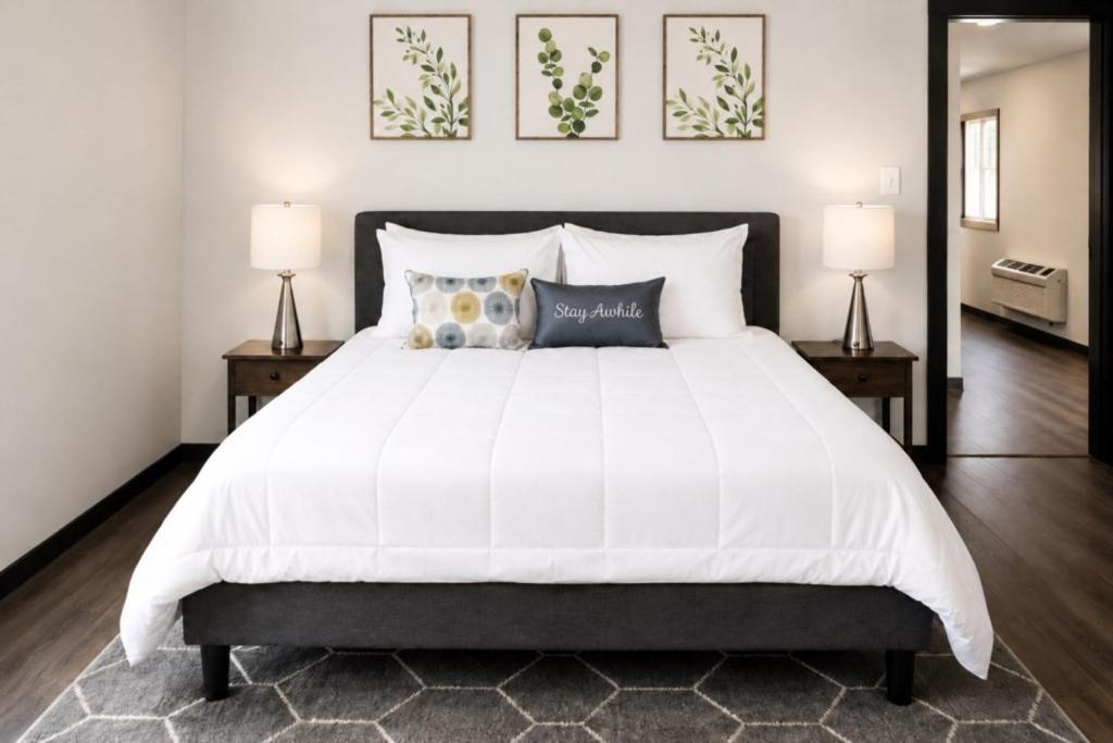 a bedroom with a large white bed with two lamps at Spacious Private Queen Studio Near Downtown in Muskegon