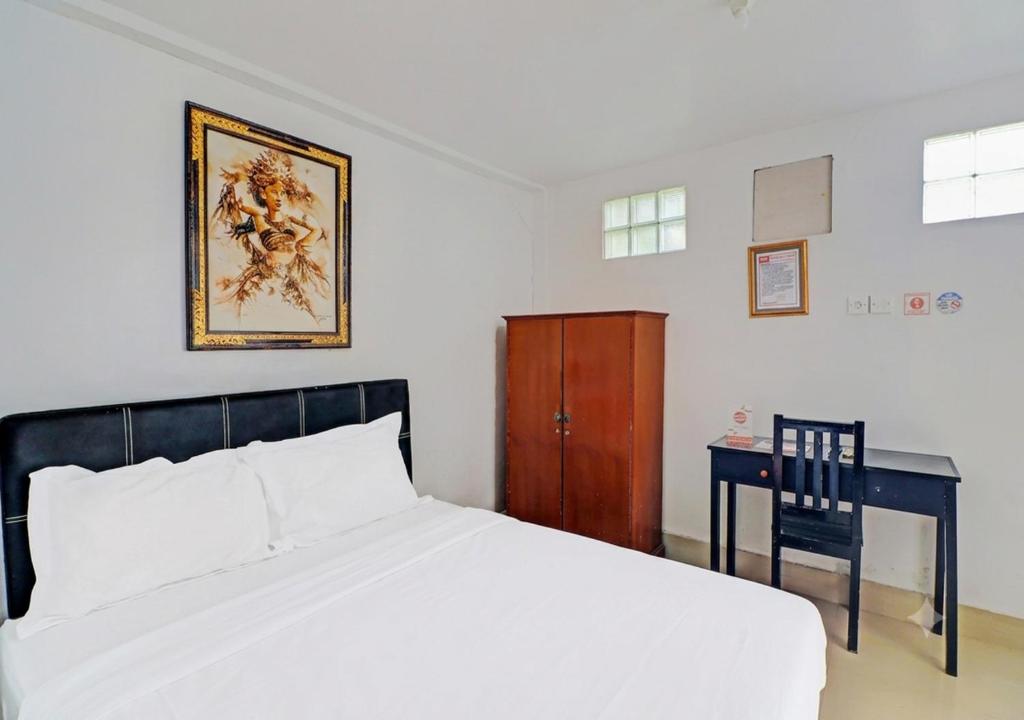 a bedroom with a bed and a table and a chair at Ari Gusti Residence in Dalung
