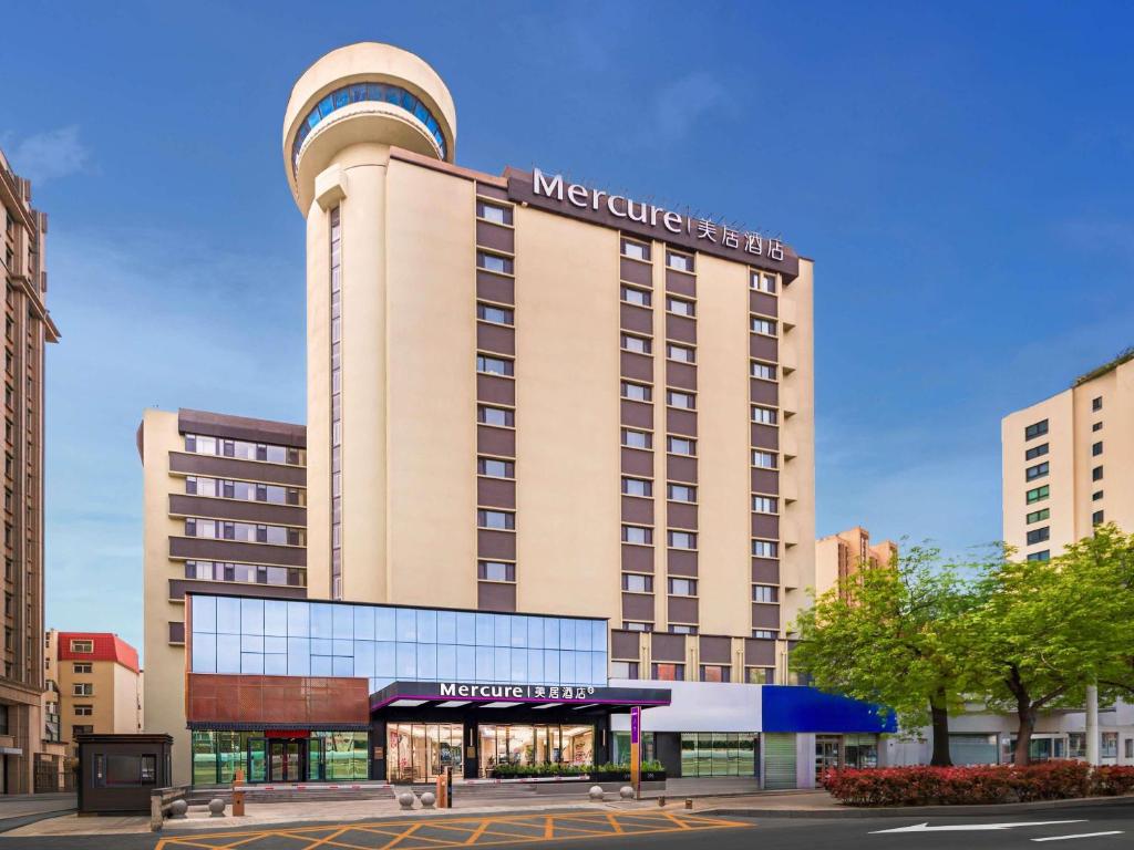 a hotel building with a sign on top of it at Mercure Qingdao May Fourth Square in Qingdao