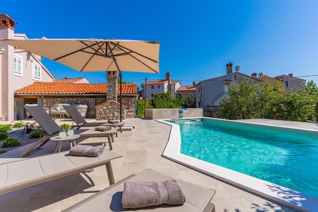 a pool with chairs and an umbrella next to a house at Villa Loznati in Cres