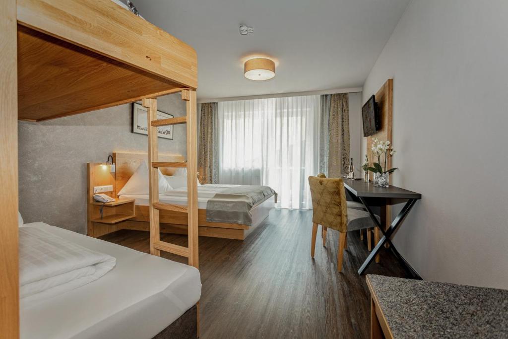 a bedroom with a bunk bed and a desk with a desk at Hotel Almrausch in Saalbach-Hinterglemm