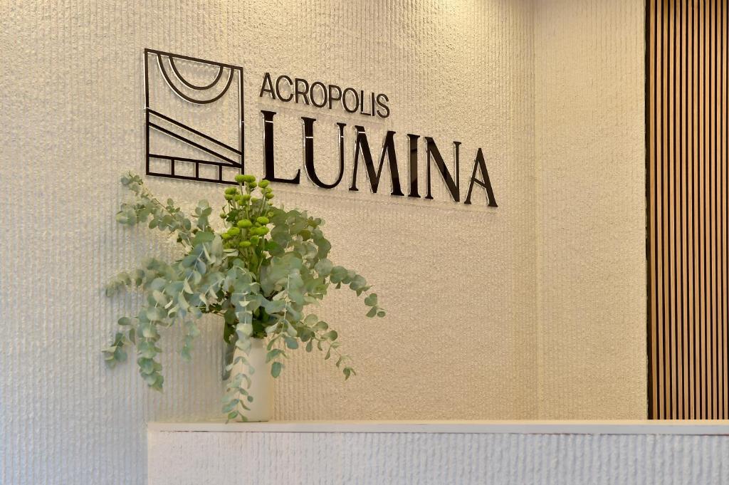 a plant in a vase on a wall with a sign at Acropolis Lumina in Athens