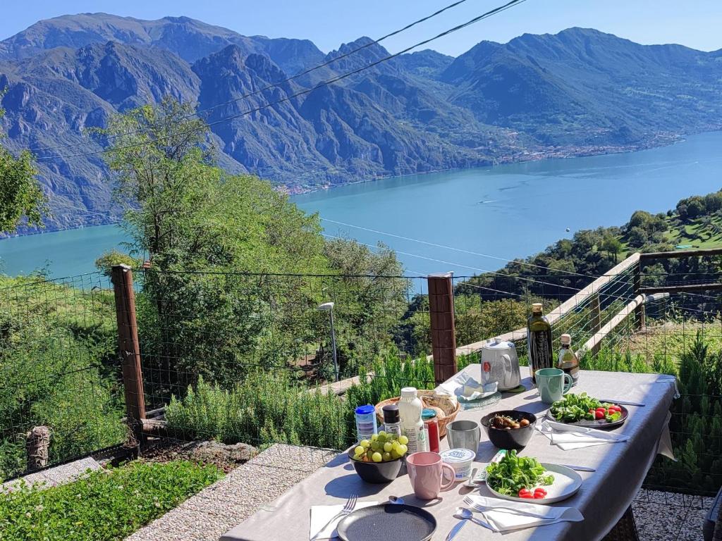 a table with food and a view of a lake at EnjoyIseoLake - Oasi Azzurra - Cosy flat with a terrace and a great view over lake and mountains in Fonteno