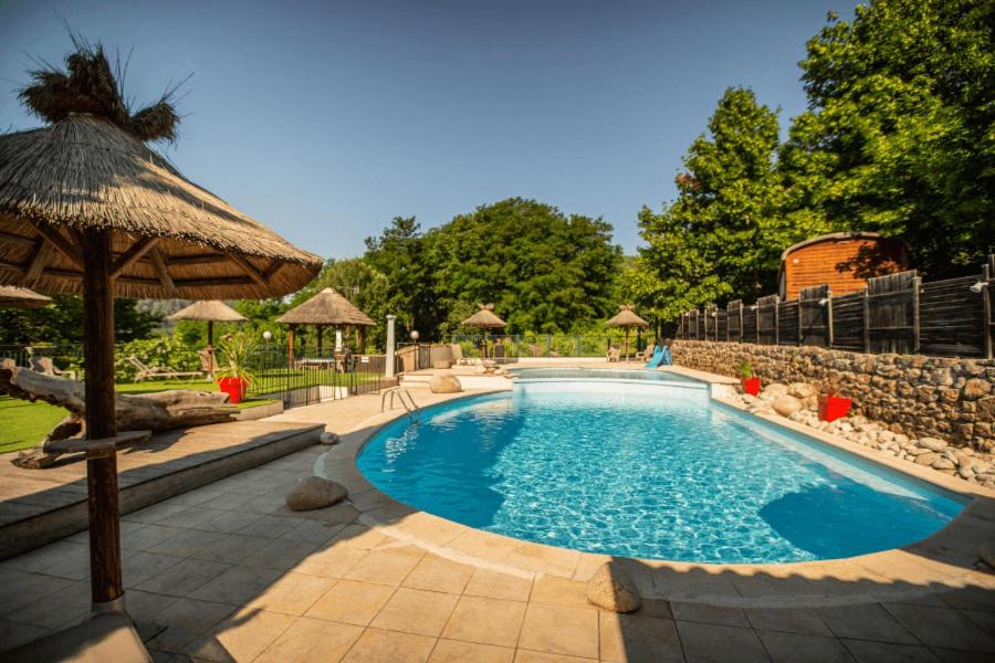 a large swimming pool with an umbrella at Camping Ushuaïa Villages Les Cruses in Ribes