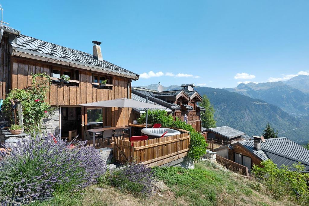 a house on a hill with a deck with an umbrella at Chalet La Grange Courchevel in Courchevel
