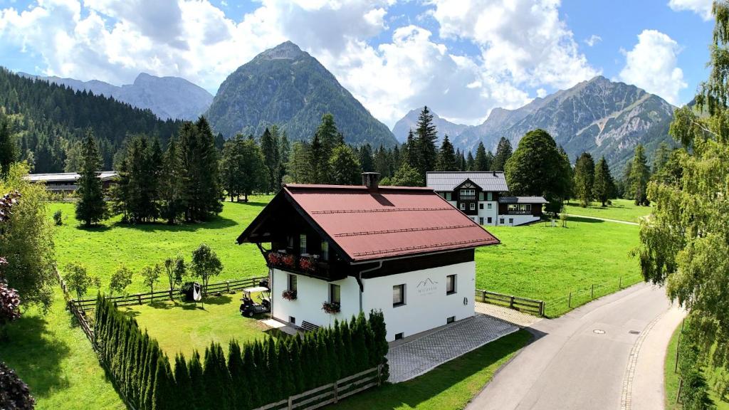 a small house in a field with mountains in the background at Michelis Cottage - Achensee in Pertisau