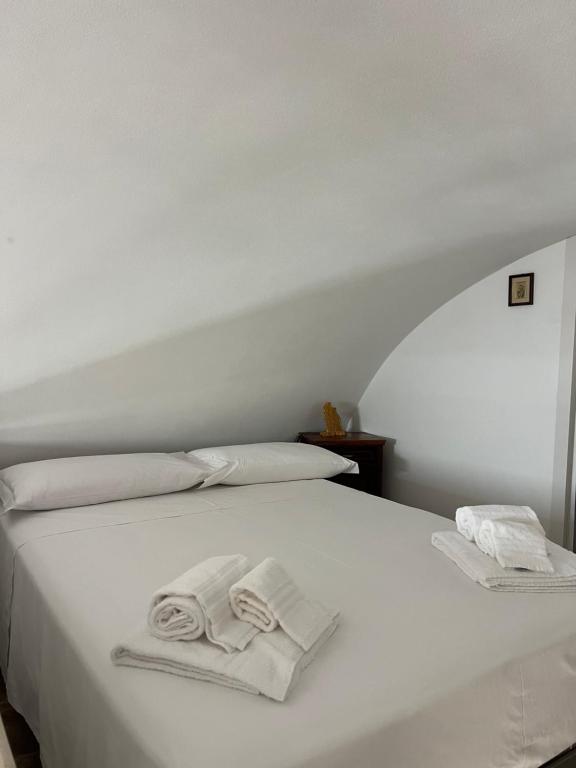 a white bed with two folded towels on it at Dimora Lieta in Pisticci