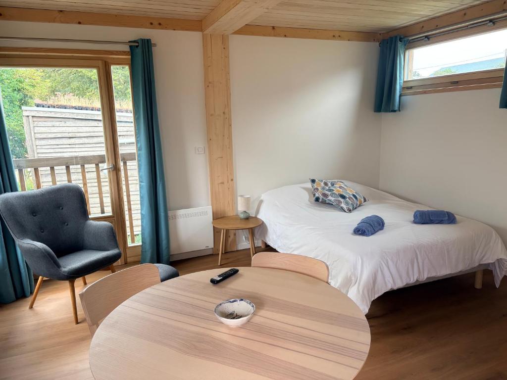 a room with two beds and a table and a chair at Les Gîtes du Chênelet in Landrethun-le-Nord