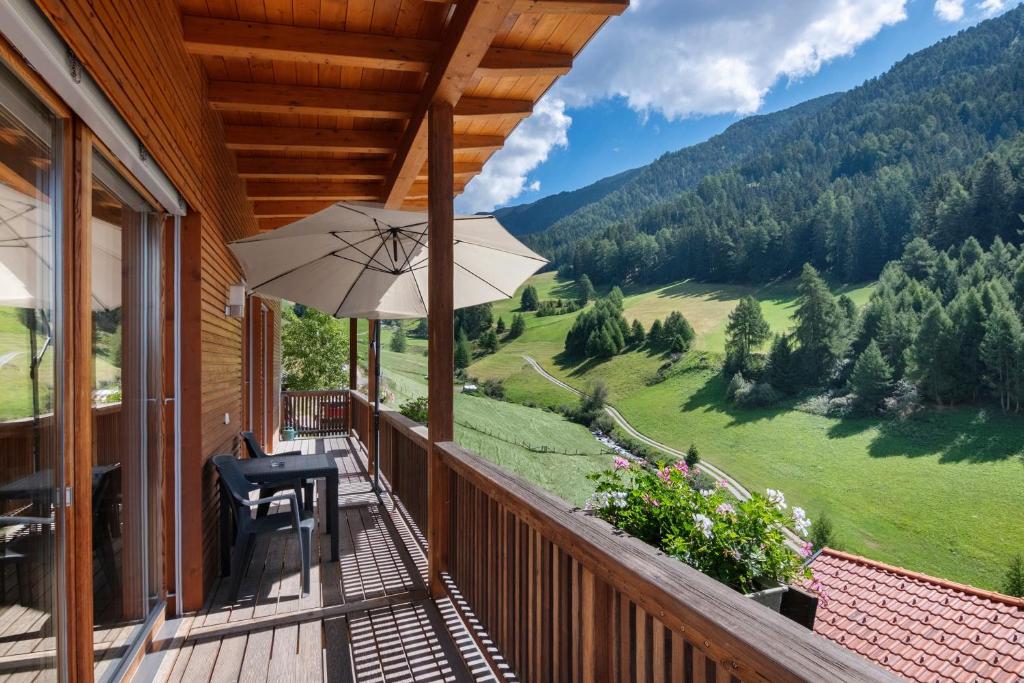 a balcony with a table and chairs and an umbrella at Pritscheshof Ferienwohnung Balkon in Malles Venosta