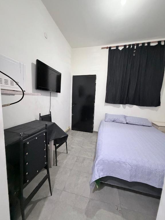 a bedroom with a bed and a desk and a tv at rinconcito en floresta in Buenos Aires