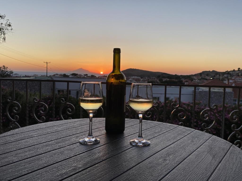 a bottle of wine and two glasses on a table at Two Mills Apartments in Myrina