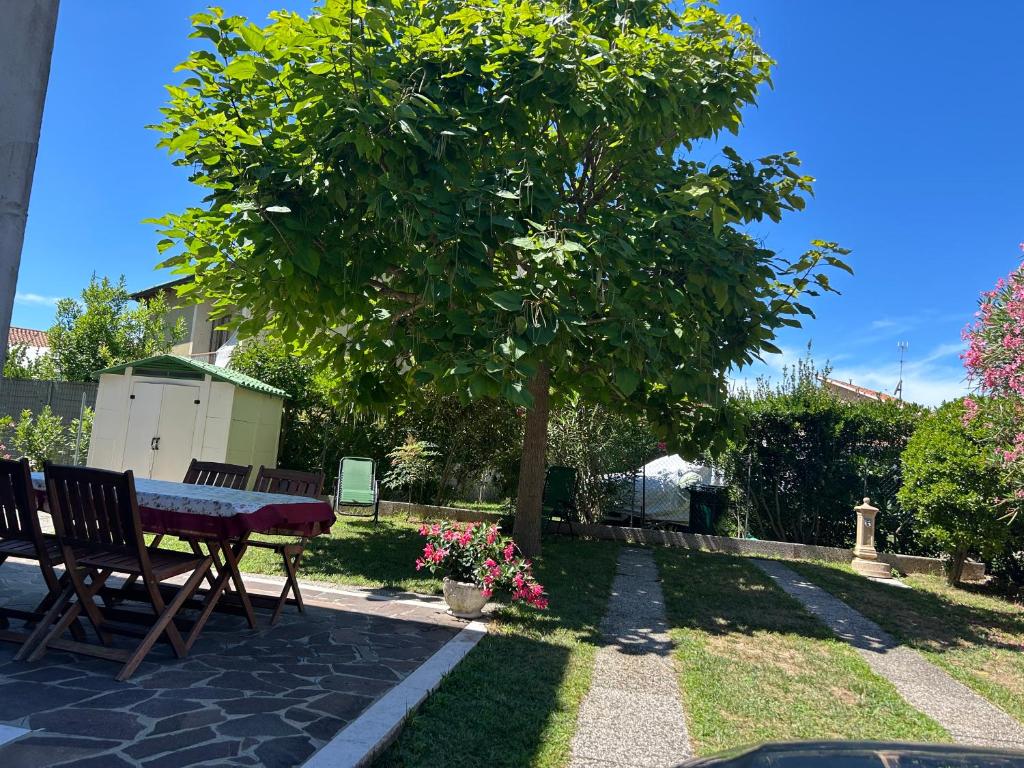 a table and chairs under a tree in a yard at Villa bifamiliare per famiglie con giardino. in Cavallino-Treporti