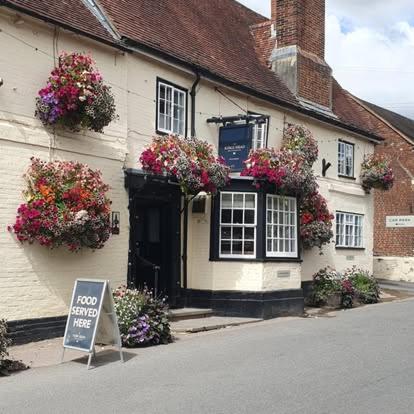 a white building with flowers on the side of it at The Kings Head in Whiteparish