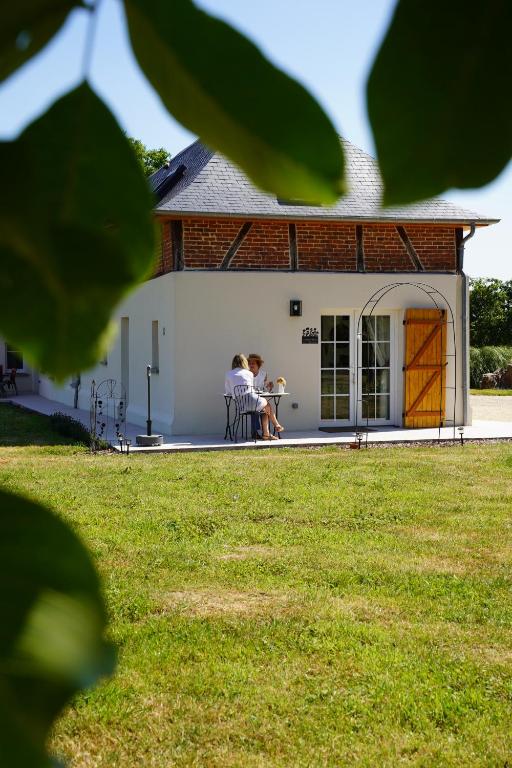 two people sitting at a table outside of a building at Le loft d'Adrien, une ode à la douc'Eure, classé 3 étoiles, accueil vélo in Beauficel-en-Lyons