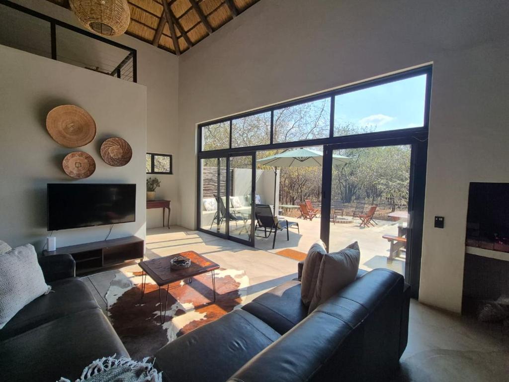 a living room with a blue couch and a large window at Mukaya Haven in Marloth Park