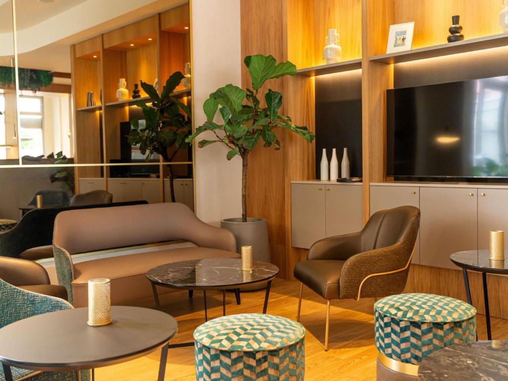 a living room with tables and chairs and a room with tables at Mercure Colmar Centre Unterlinden in Colmar