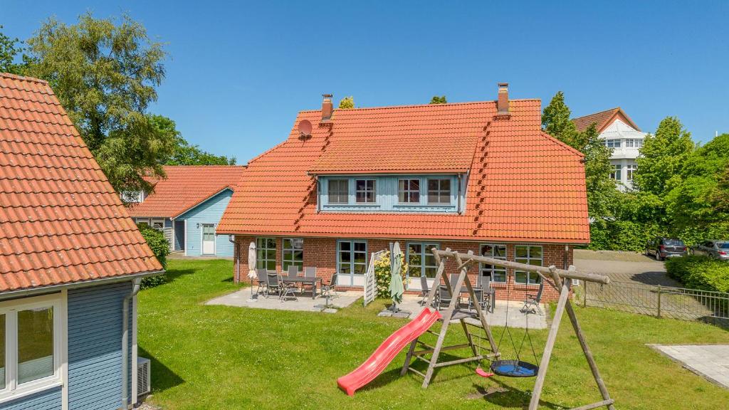 a house with an orange roof with a playground at Heideröschen Park Heideröschen 9 in Zingst