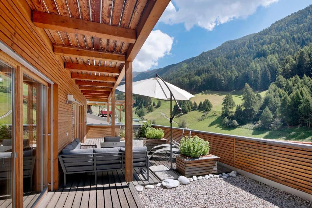 a deck with chairs and an umbrella on a house at Pritscheshof Ferienwohnung Terrasse in Malles Venosta
