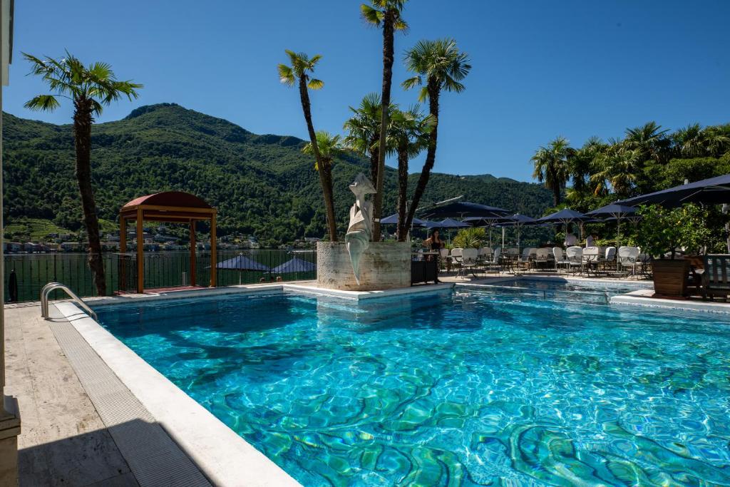 a swimming pool with a fountain and palm trees at Swiss Diamond Hotel & Spa in Morcote