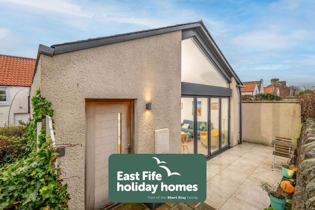 a house with a sign that reads east fire holiday homes at Tylosand, Allan Place No 8 in Earlsferry