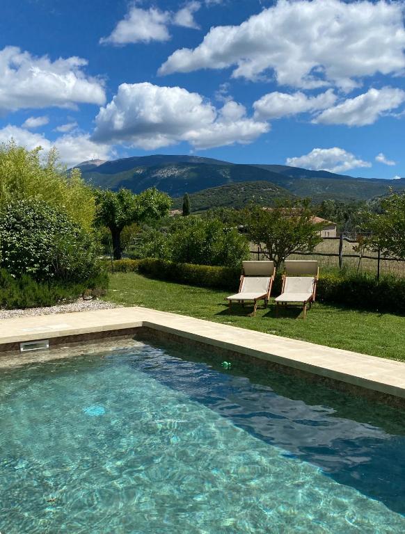 a swimming pool in a yard with two chairs at Mas de grange neuve in Mollans-sur-Ouvèze