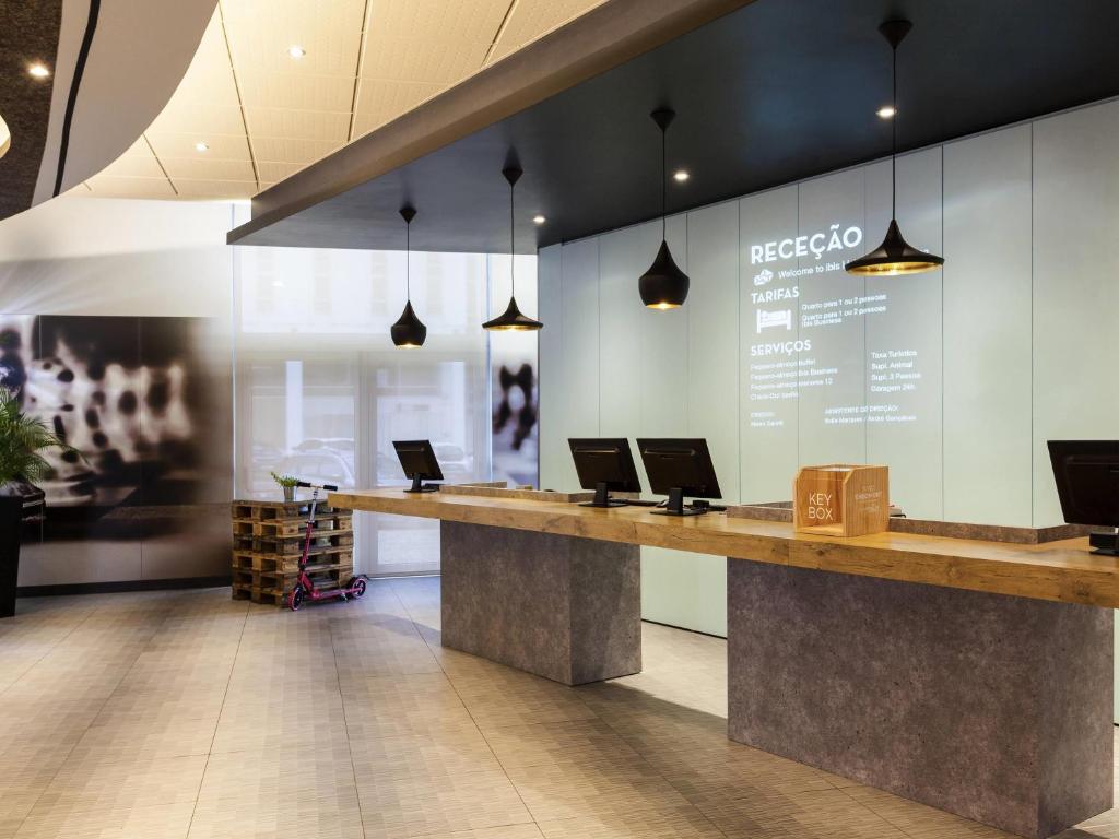 a lobby with a counter with laptops on it at Hotel ibis Lisboa Jose Malhoa in Lisbon