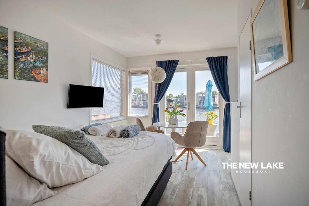 a bedroom with a bed and a desk and windows at The New Lake Boathouse in Amsterdam