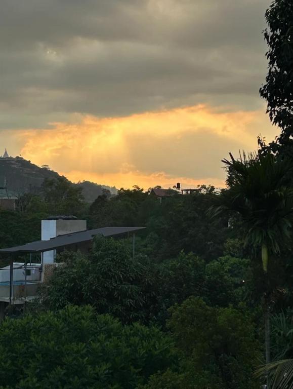 a sunset over a city with trees and a building at Dilshan Cottage in Ella