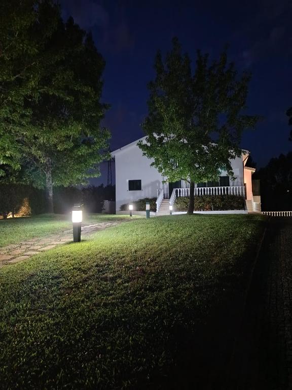 a white building with lights in a yard at night at Casa do Alto in Recarei