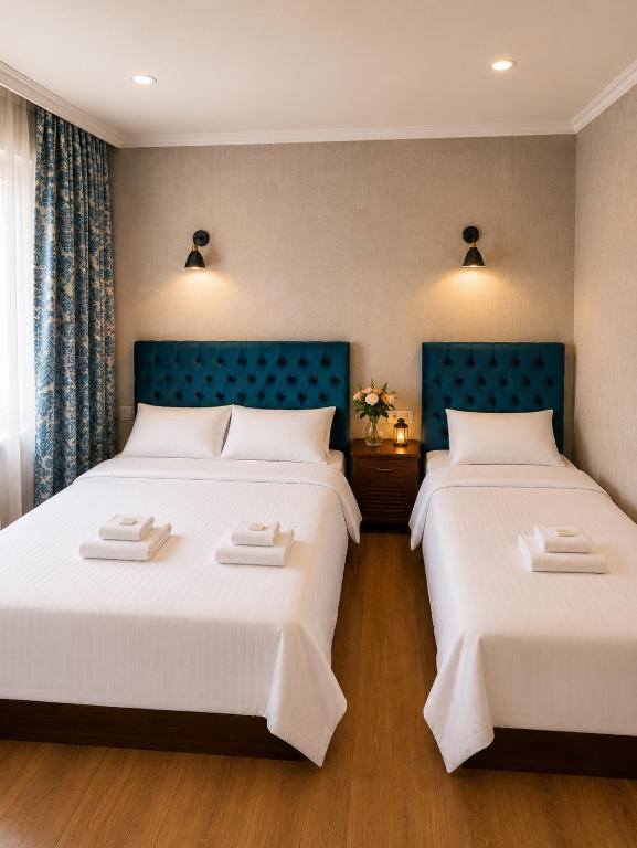 two beds in a hotel room with white sheets at Hotel Kalanga in Tbilisi City