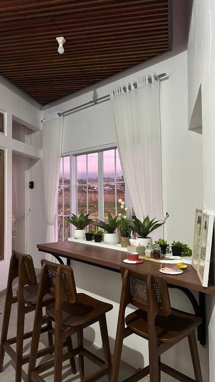 a dining room table with chairs and a large window at Naeera Inn Wonosobo Dieng in Kalibeber