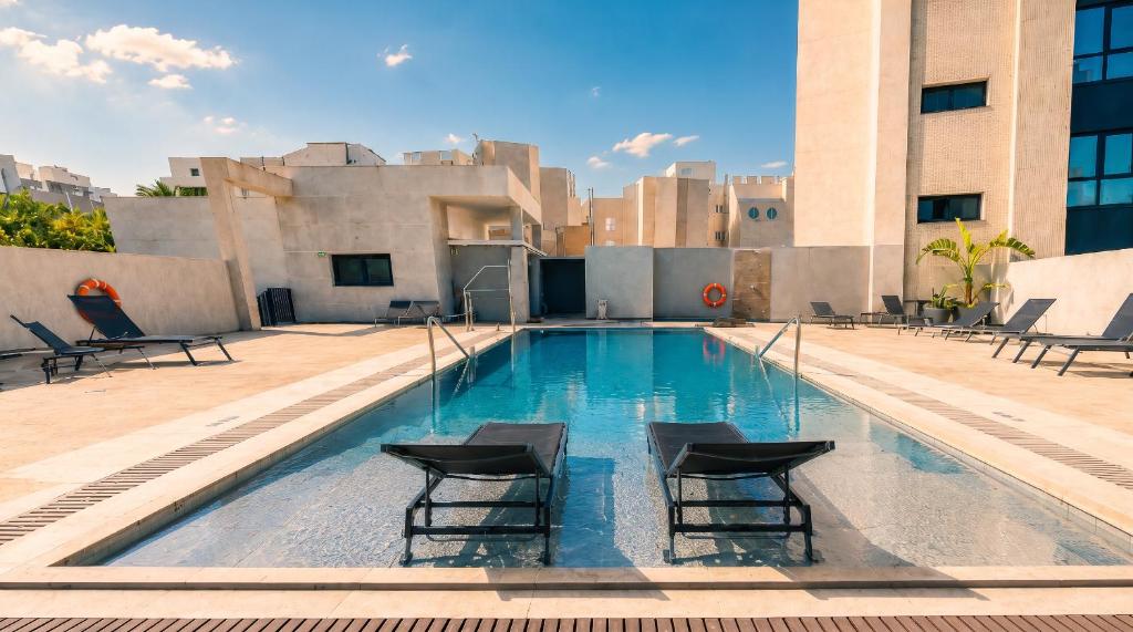 a swimming pool on the roof of a building with chairs at Vértice Indalo Almería in Almería