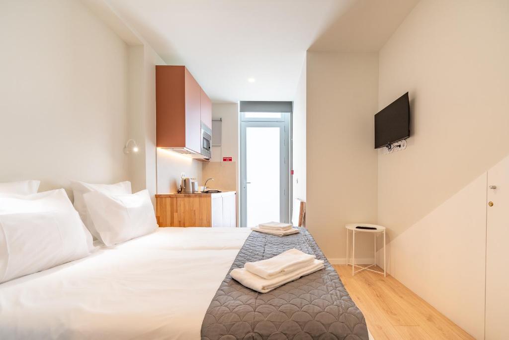 a bedroom with a white bed with a tv on the wall at Studio FAMEUSE in Matosinhos