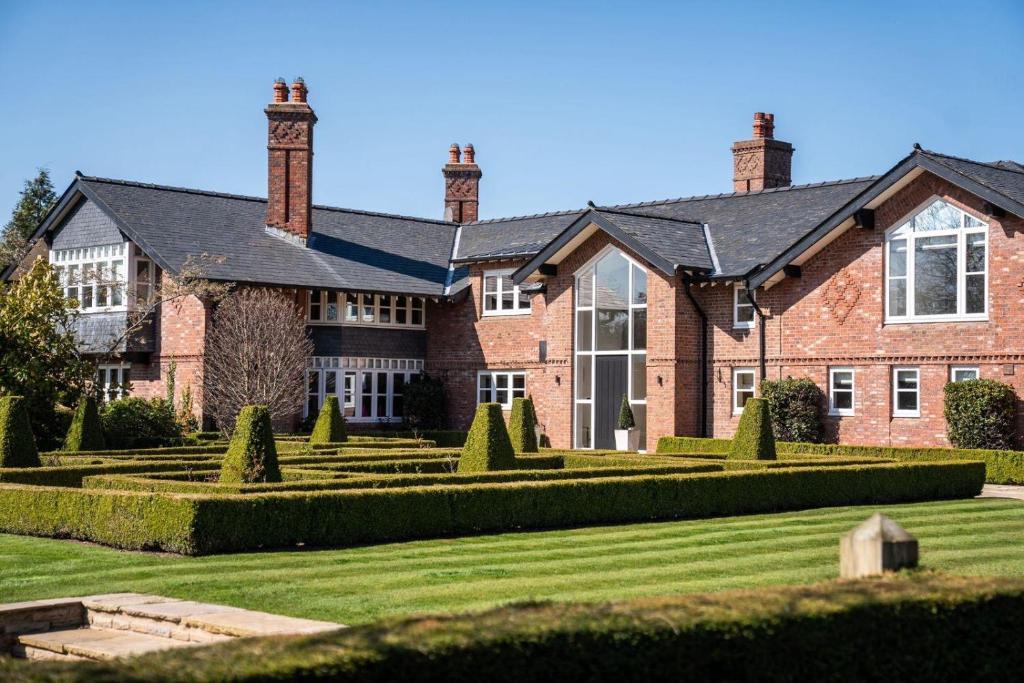 a large red brick house with a large yard at Fernside Barn - Studio Apartment in Pickmere