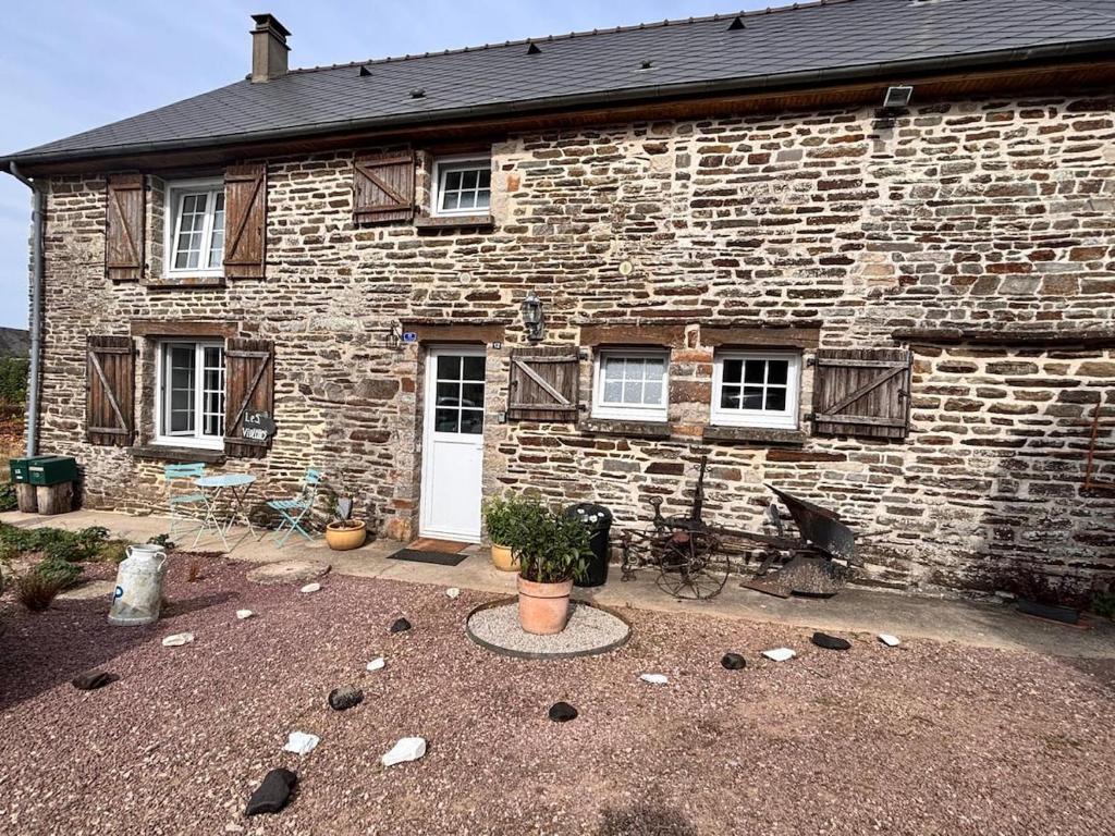 a brick building with a white door and windows at Le Gîte des Violettes in Ger