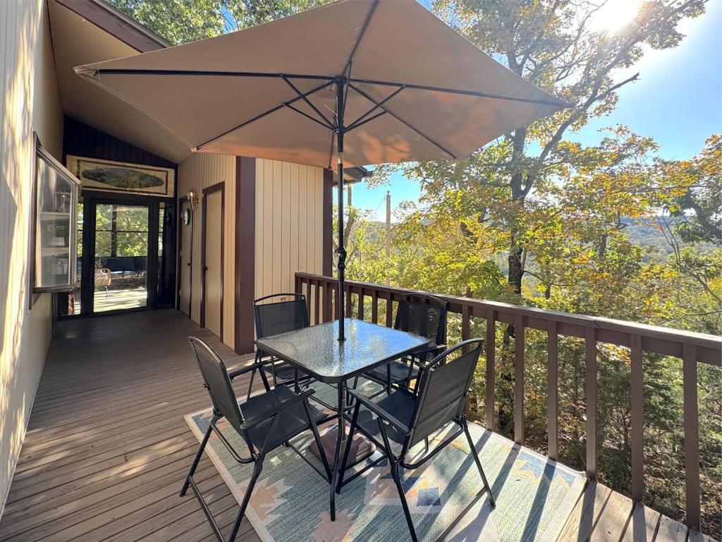 a table and chairs on a deck with an umbrella at The Treehouse on Table Rock in Eureka Springs
