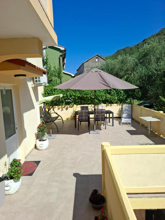a patio with an umbrella and a table and chairs at LEVANDA in Supetarska Draga