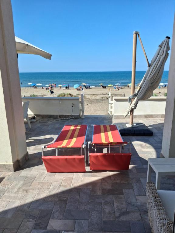 a red and yellow bed on the beach at the suite on the beach in Torvaianica