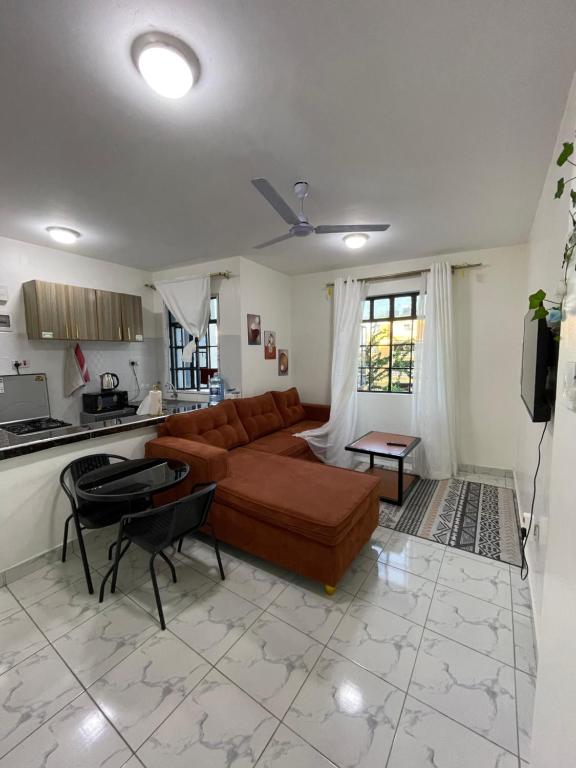a living room with a brown couch and a kitchen at cozy 1bedroom mombasa bamburi near the beach with hot shower, Netflix, Secured parking 07&07 for 95 then 61to18 in Mombasa