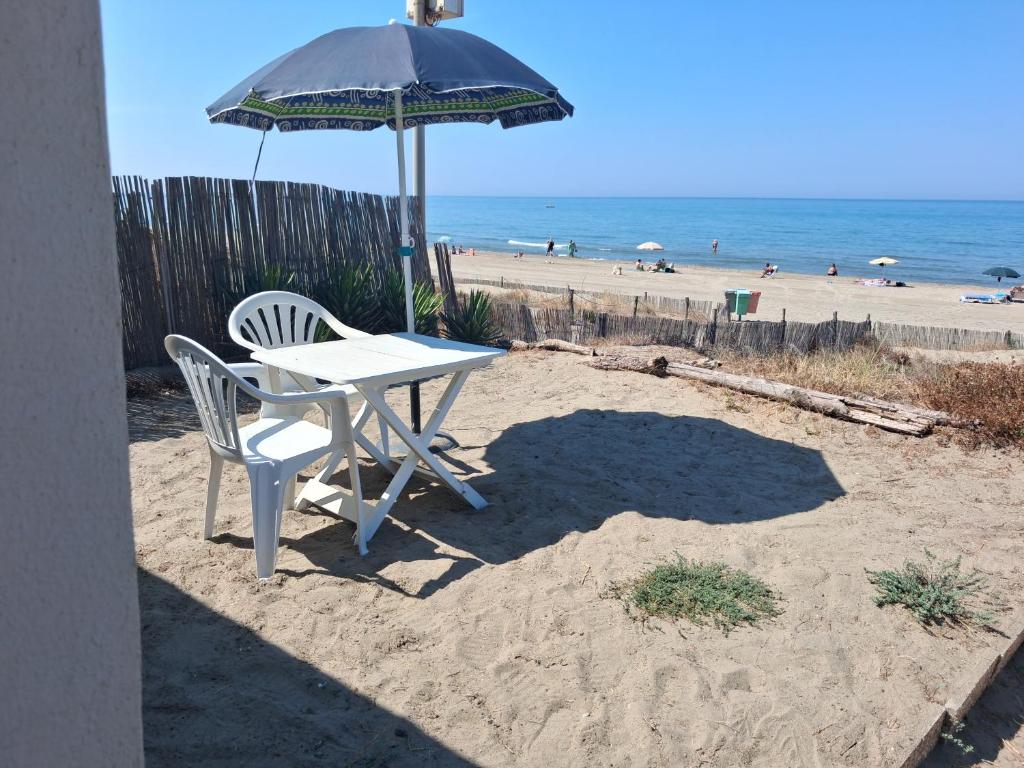 a table and chairs under an umbrella on the beach at CASINA SULLa SABBIA in Torvaianica