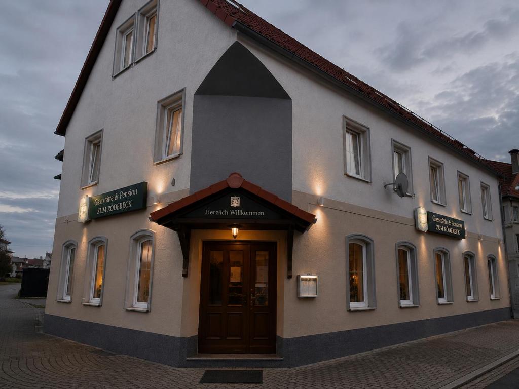 a large white building with a door on a street at Pension Zum Rödereck in Zeithain