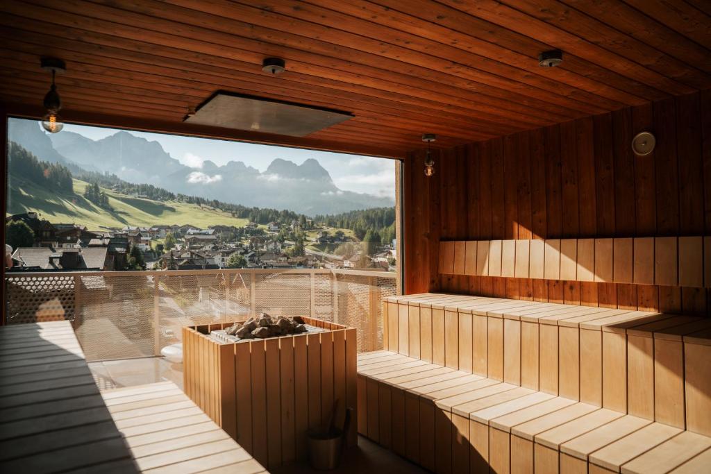 a room with a large window with a mountain view at Hotel Tofana in San Cassiano