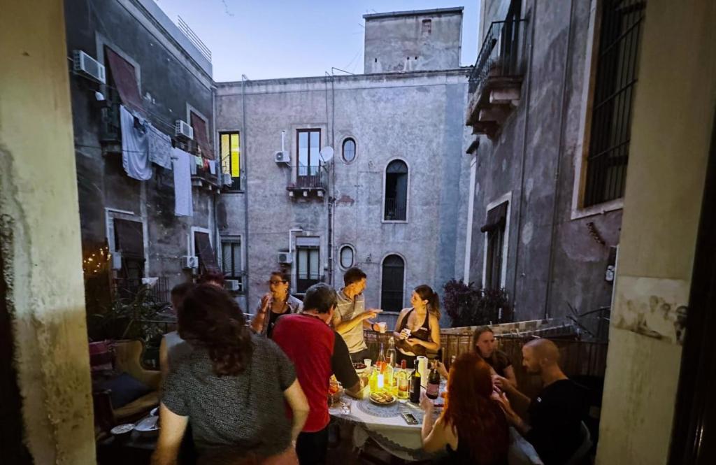 a group of people sitting around a table in an alley at Casa Verdi - House of Travelers in Catania