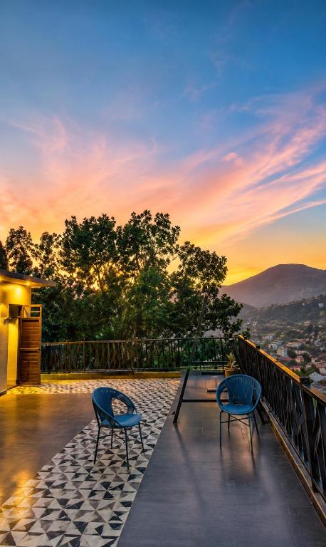 two chairs and a table on a balcony with a sunset at Summer Stays Boho in Bhīm Tāl