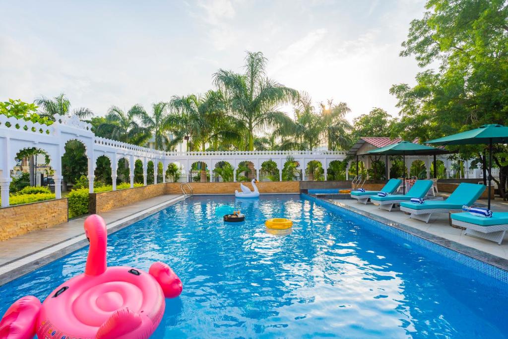 a pool at a resort with a pink pool toy in the water at Manas Resort Udaipur in Udaipur
