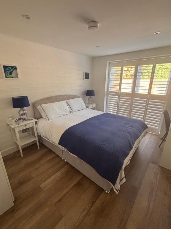 a bedroom with a large bed with a blue blanket at Mudeford Breeze in Mudeford