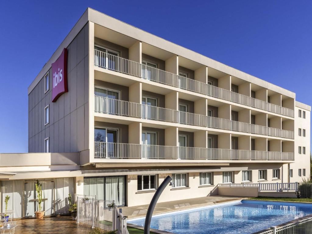 an image of a hotel with a swimming pool at ibis Tarbes Odos in Odos