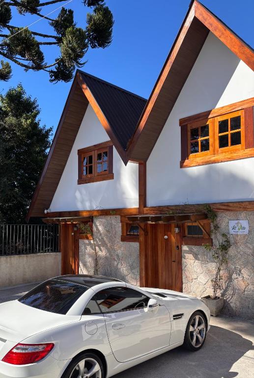 a white car parked in front of a house at Le Ville - Campos do Jordão in Campos do Jordão